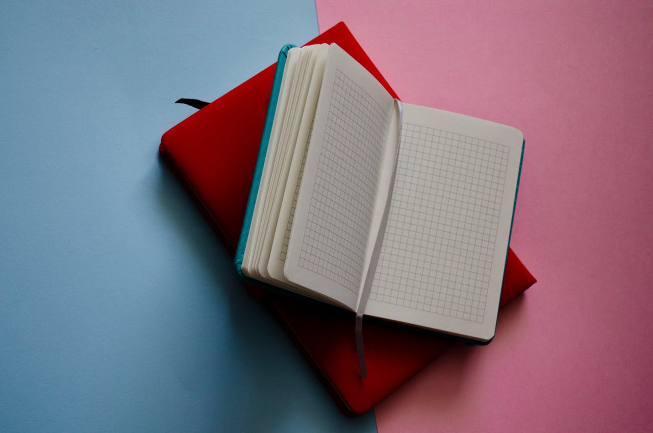 An open notebook with grid paper on a vibrant pink and blue background.